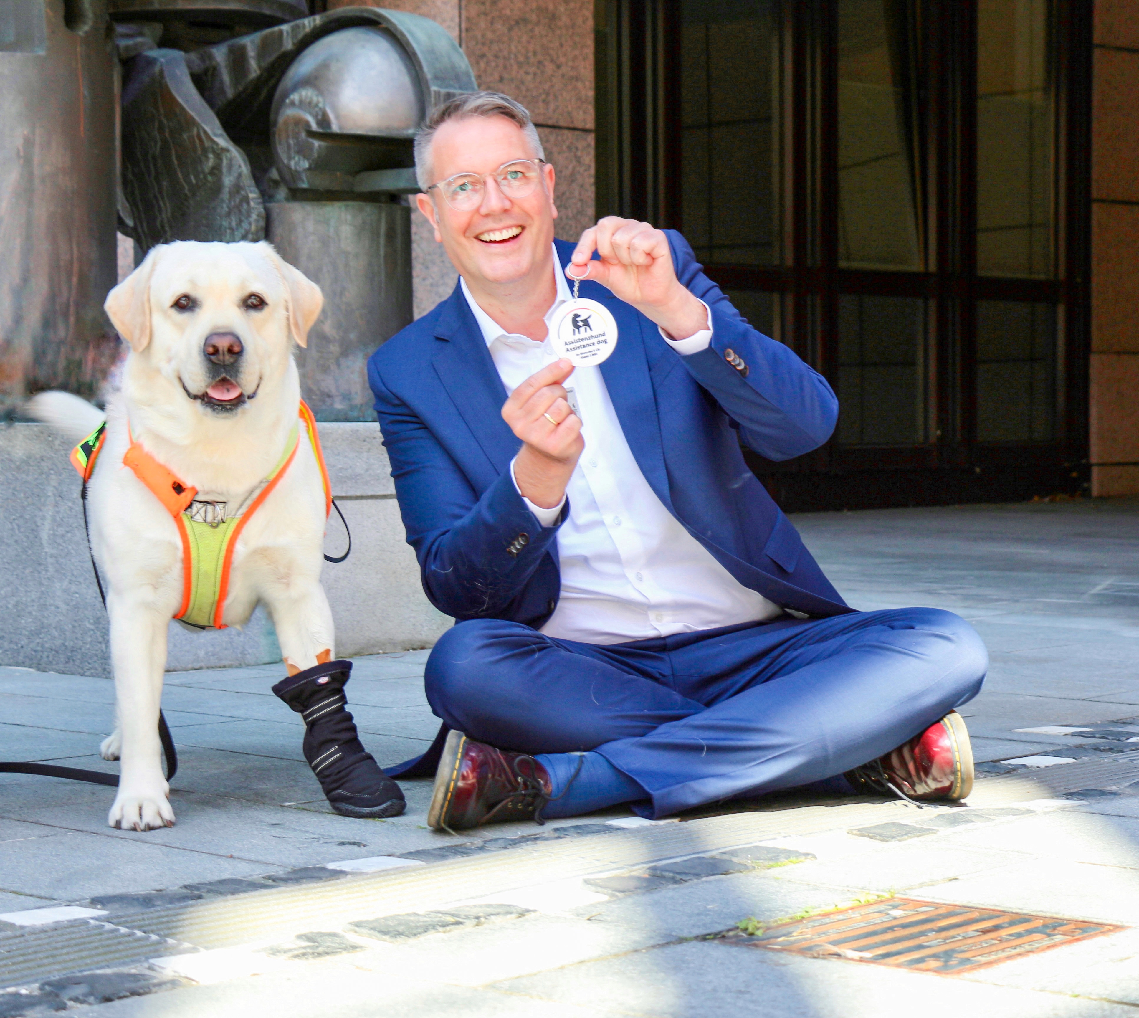 Der rheinland-pfälzische Sozialminister Alexander Schweitzer (Foto) hat Assistenzhund Oskar und seinem Menschen die Plakette überreicht. Foto: © MASTD