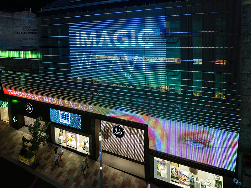 Transparente Medienfassade Imagic Weave in Andorra. Die Videoinhalte scheinen unmittelbar vor der Fassade zu schweben, ohne diese vollständig zu verdecken. Foto: © David Cabrera