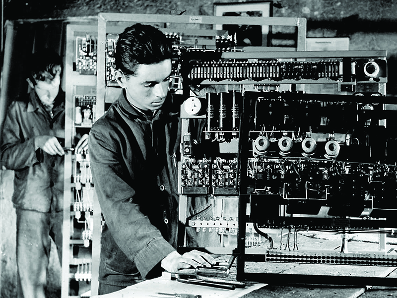 Blick in die Vergangenheit: Ein Industrieschlosser der Firma Nunn kantet ein Blechteil und baut eine Steuerung - damals wurden alle Aufzugskomponenten wie Steuerung und Treibscheiben noch von Hand geschmiedet, gefeilt und geschliffen. Foto: © Nunn-Aufzüge Blick in die Vergangenheit: Ein Industrieschlosser der Firma Nunn kantet ein Blechteil und baut eine Steuerung - damals wurden alle Aufzugskomponenten wie Steuerung und Treibscheiben noch von Hand geschmiedet, gefeilt und geschliffen. Foto: © Nunn-Aufzüge