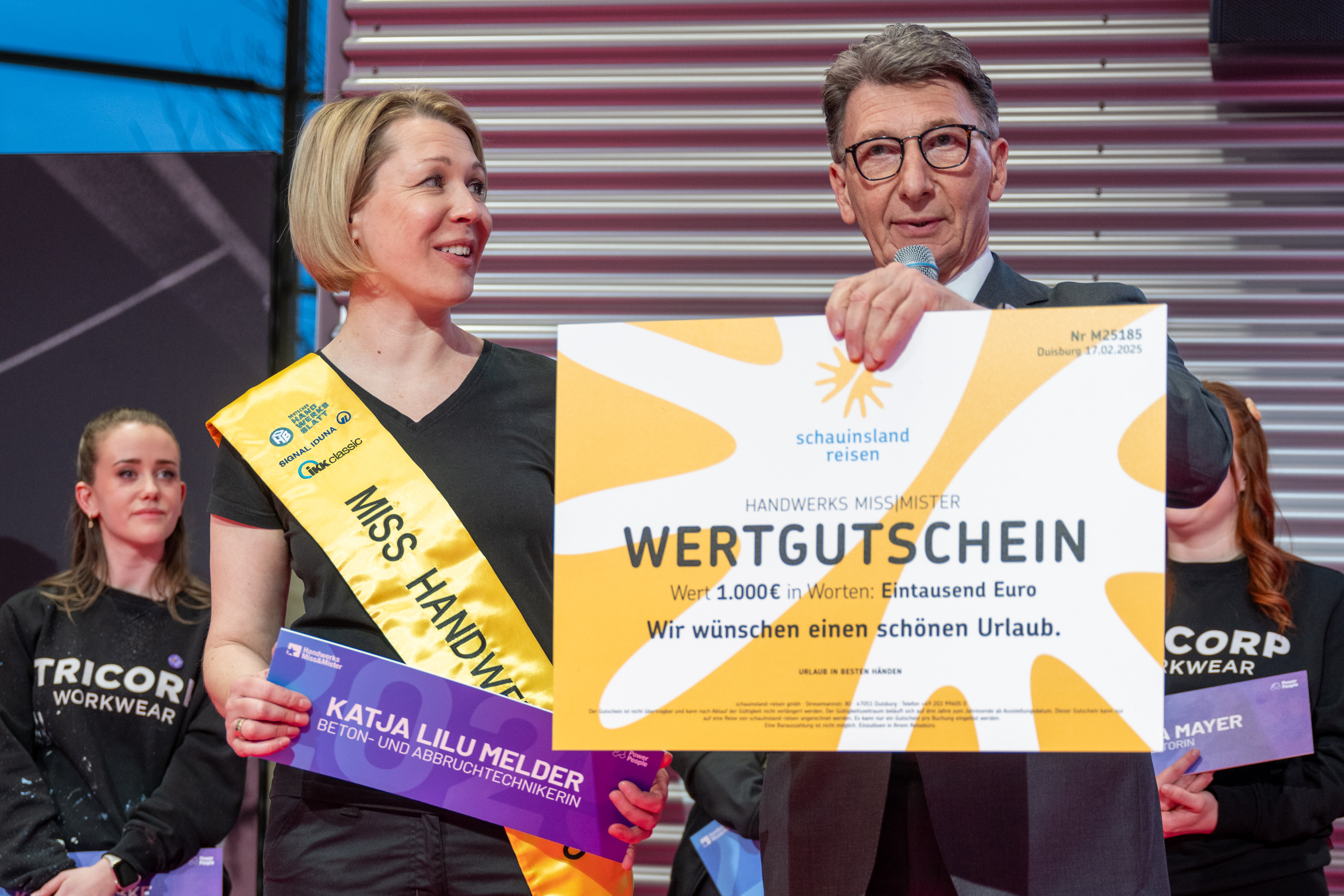 Katja freute sich bei der Sieger&shy;ehrung zu Miss Handwerk 2025 sehr, als ihr der Reisegutschein von schauinsland-reisen von Jurymitglied Ulrich Leitermann (SIGNAL IDUNA) &uuml;berreicht wurde. Foto: © Thomas Plettenberg