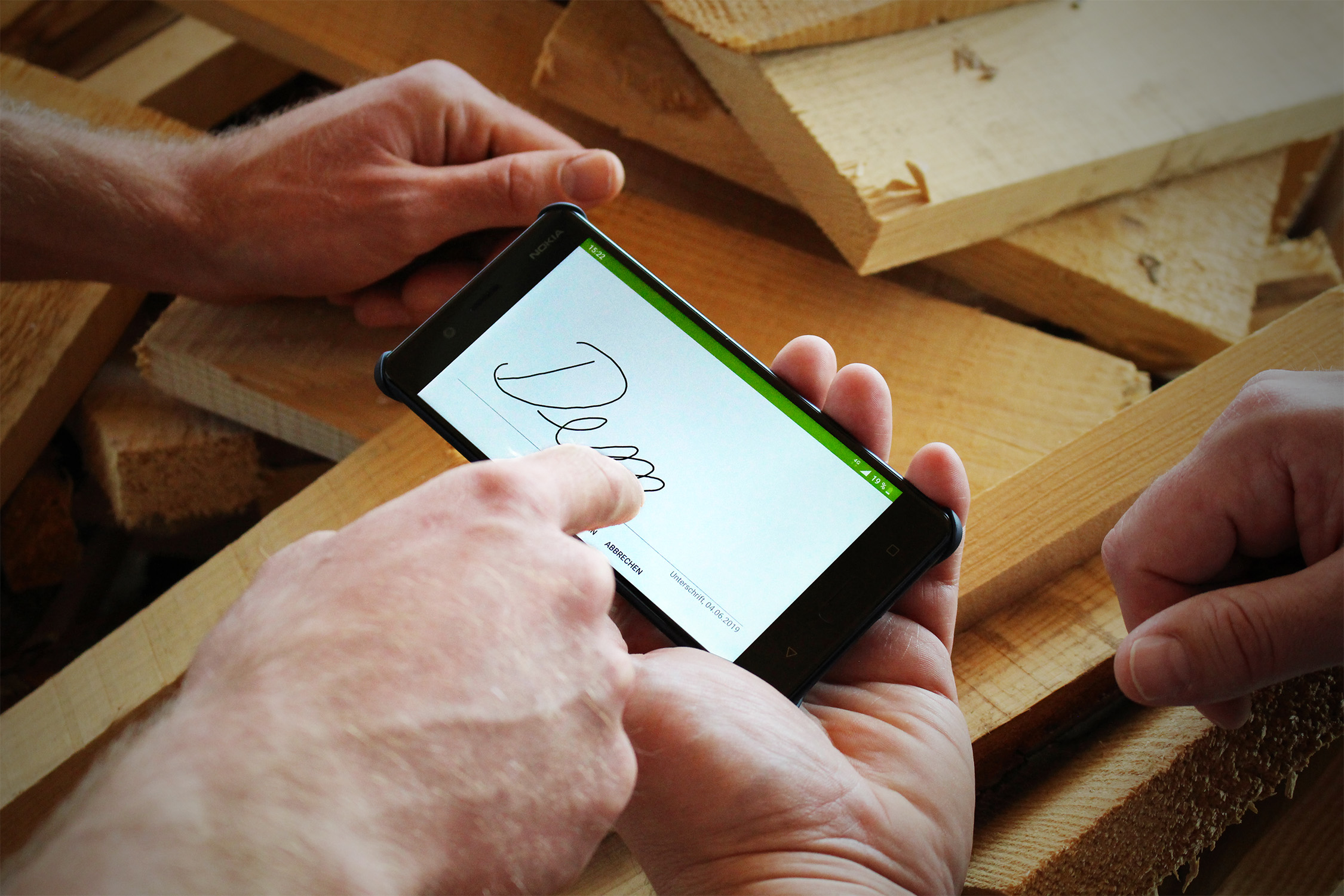 Über die App auf dem Smartphone können die Mitarbeiter ihre Stunden eintragen und sogar eine digitale Unterschrift vom Bauherrn oder Kunden einholen. Foto: © Digiholz UG