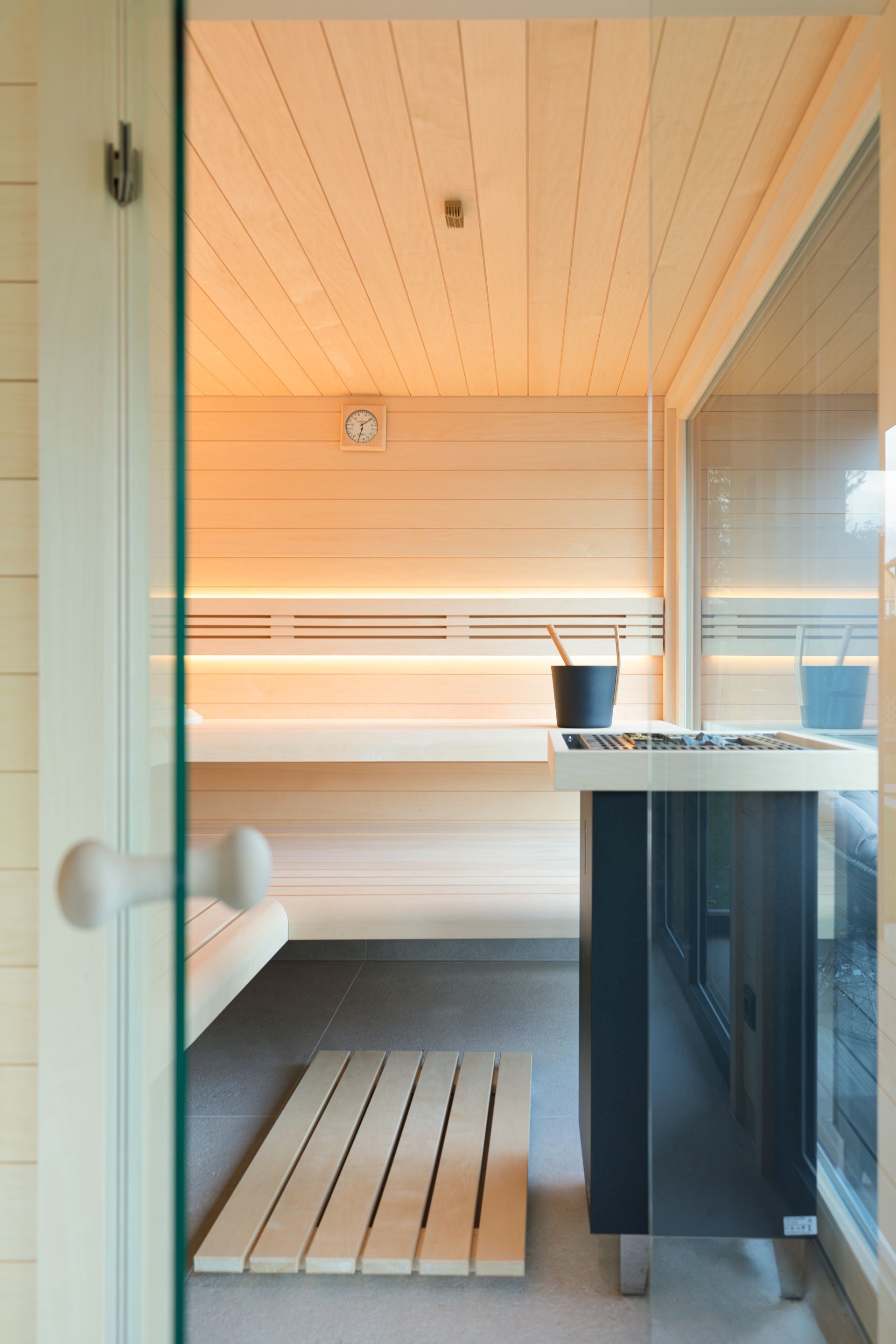 Neben bodentiefen Fenstern in der Saunakabine und dem Ruheraum wird durch die Verwendung heller Hölzer und großer Glaselemente als Raumtrenner ein großzügiges Raumgefühl in einem Saunahaus vermittelt. Foto: © Westerhoff