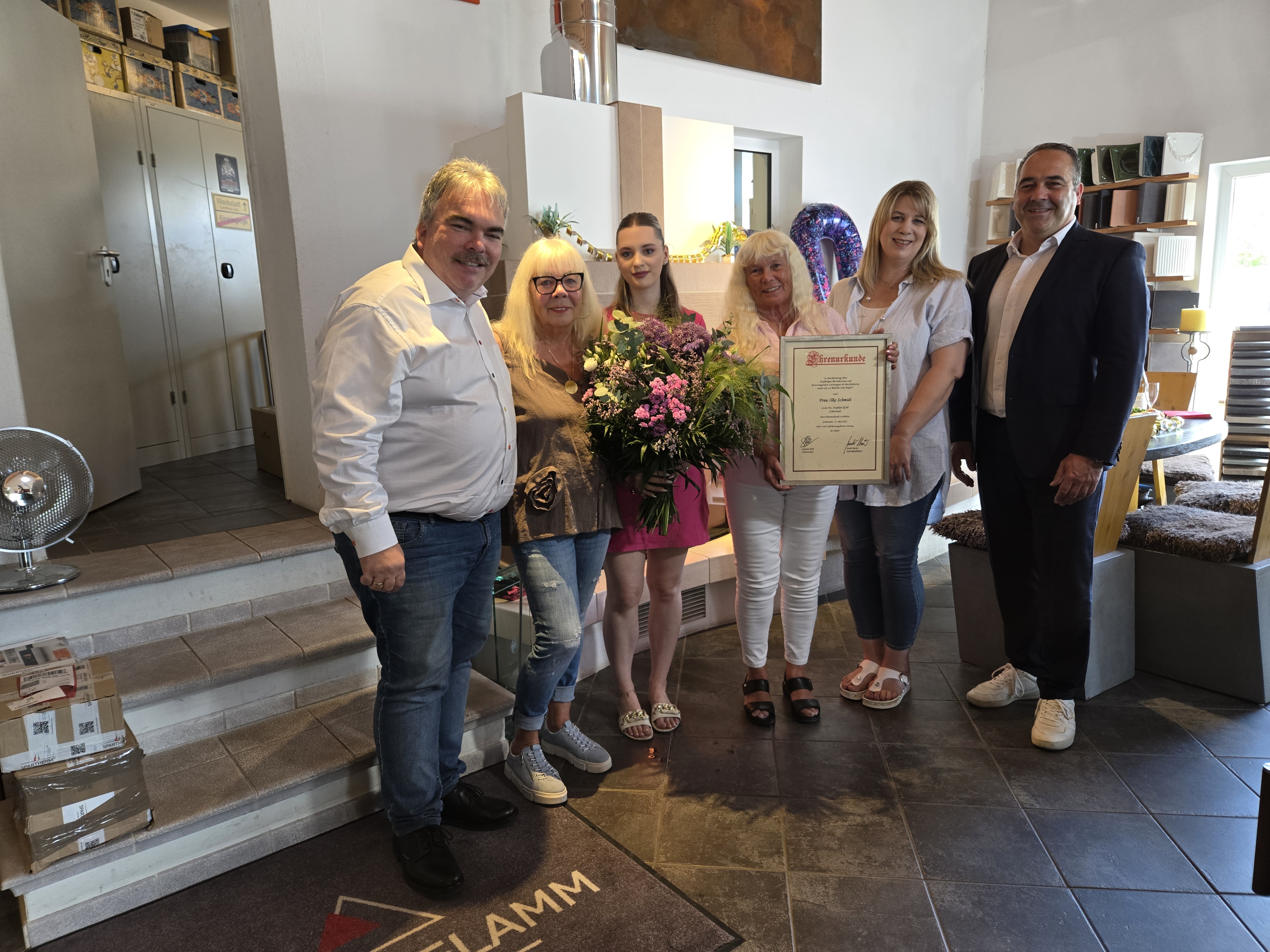 Stephan Kohl und sein Team bei der Auszeichnung von B&uuml;ro-Mitarbeiterin Ilke Schmidt, die im Mai 2025 ihr 50-j&auml;hriges Betriebsjubil&auml;um bei der Fa. Kohl gefeiert hat. Foto: © Stephan Kohl Kamin- und Kachelofenstudio