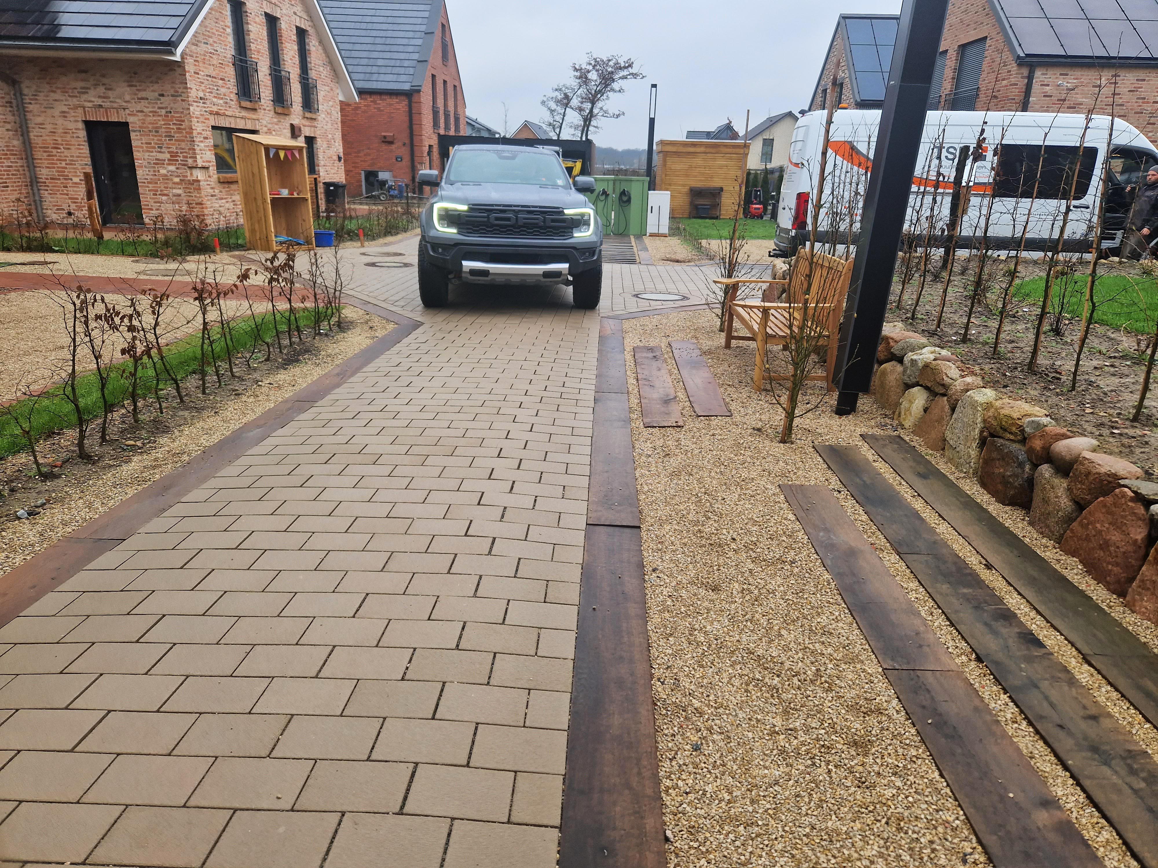 Die Stra&szlig;e links besteht aus Pflastersteinen mit wasserdurchl&auml;ssigen Fugen. Regnet es sehr stark, l&auml;uft &uuml;bersch&uuml;ssiges Wasser auf die Fl&auml;che mit HanseGrand Parking rechts, einem Klimabaustoff, der das Wasser in den Erdboden ableitet. Foto: © HanseGrand