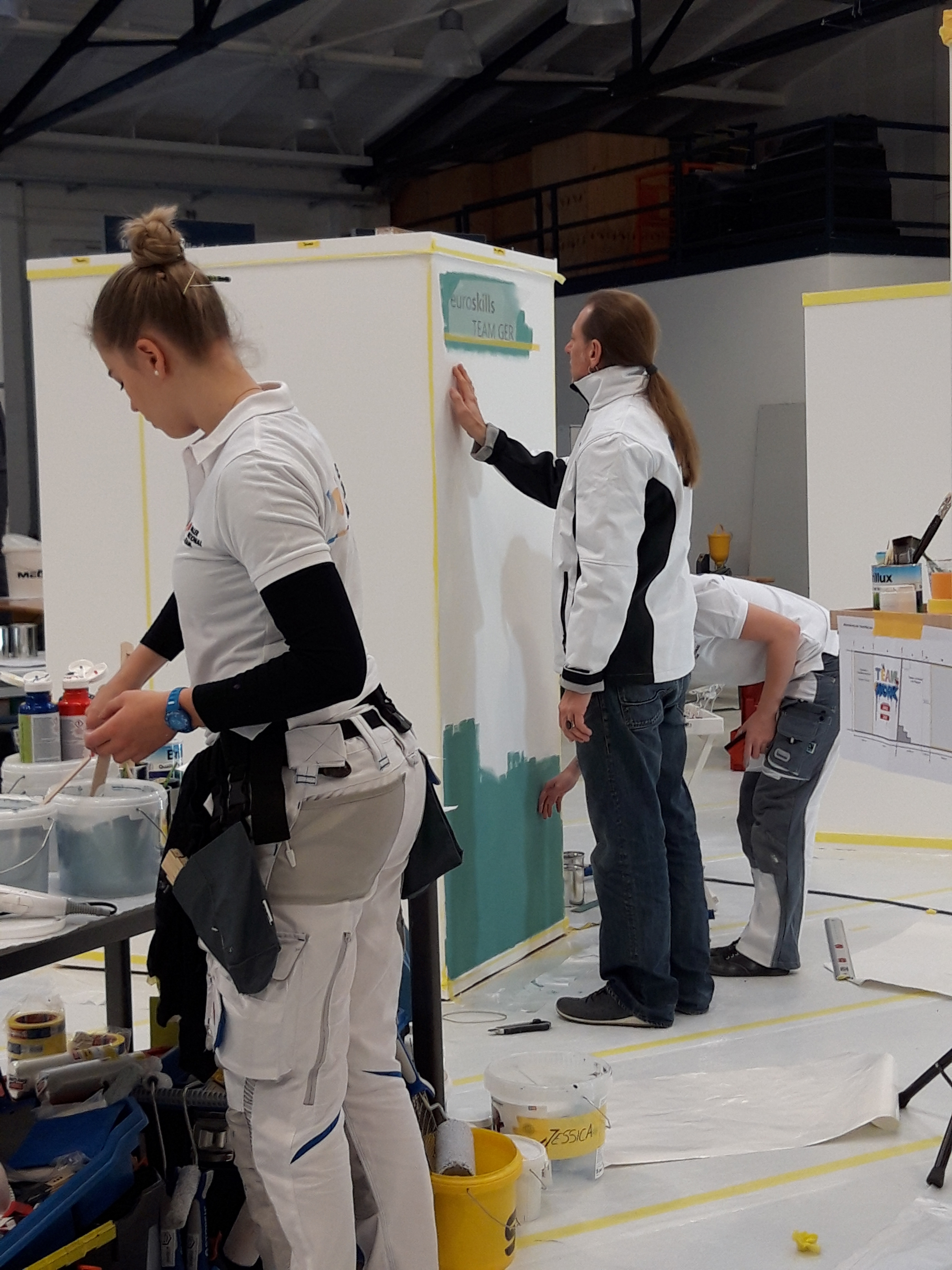 Nationaltrainer Matthias List inspiziert die Arbeiten beim Auswahlverfahren der Maler-Nationalmannschaft. Im Vordergrund: Jessica Jörges. Foto: © Bundesverband Farbe