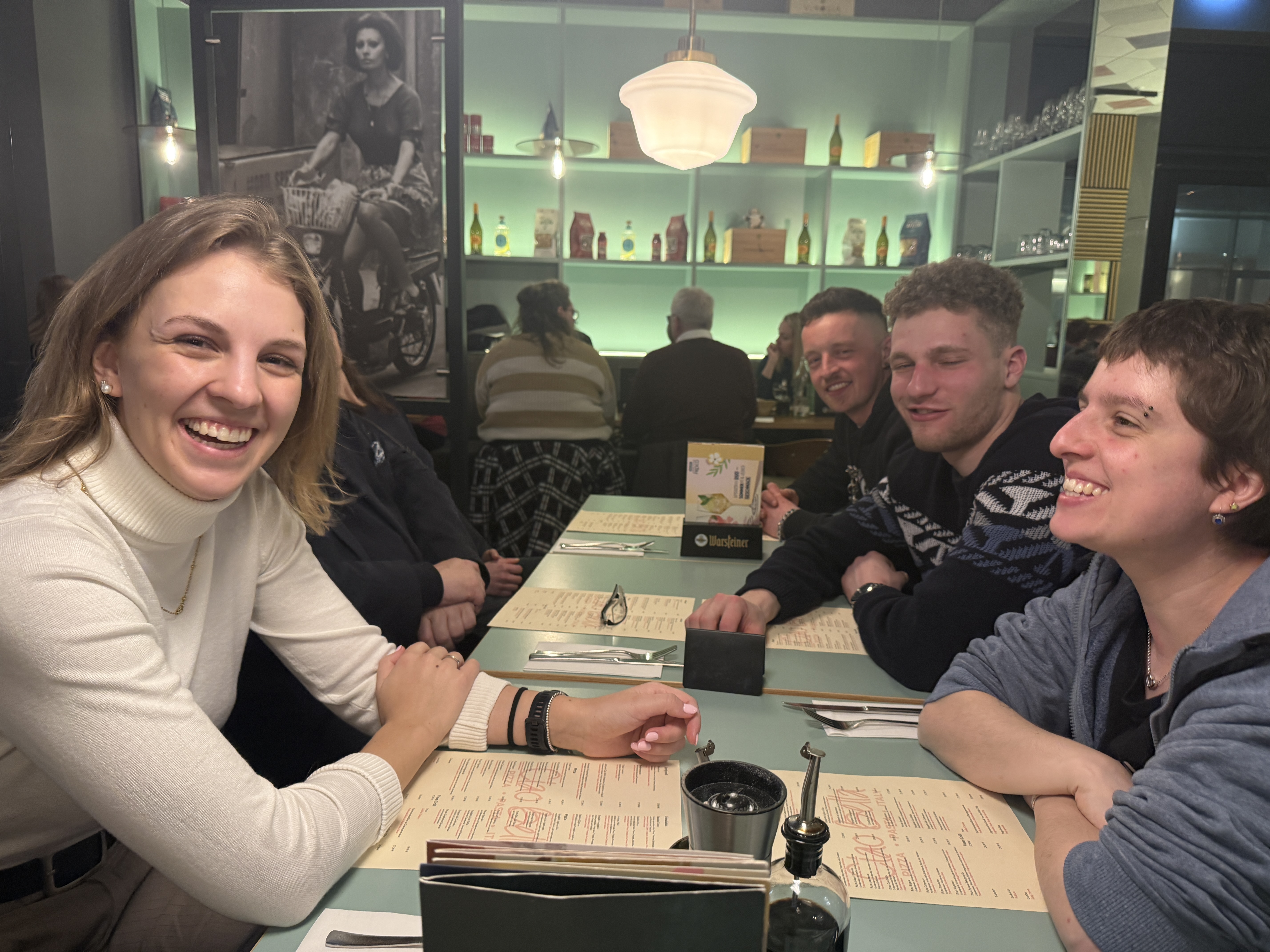 Bestatterin Emily (l.) im Gespr&auml;ch mit M&uuml;llerin Thea (r.), Stuckateur Maximilian (2.v.r.) und Ger&uuml;stbauer Hannes (3.v.r.) beim gemeinsamen Abendessen. Foto: © Wolfgang Weitzdörfer