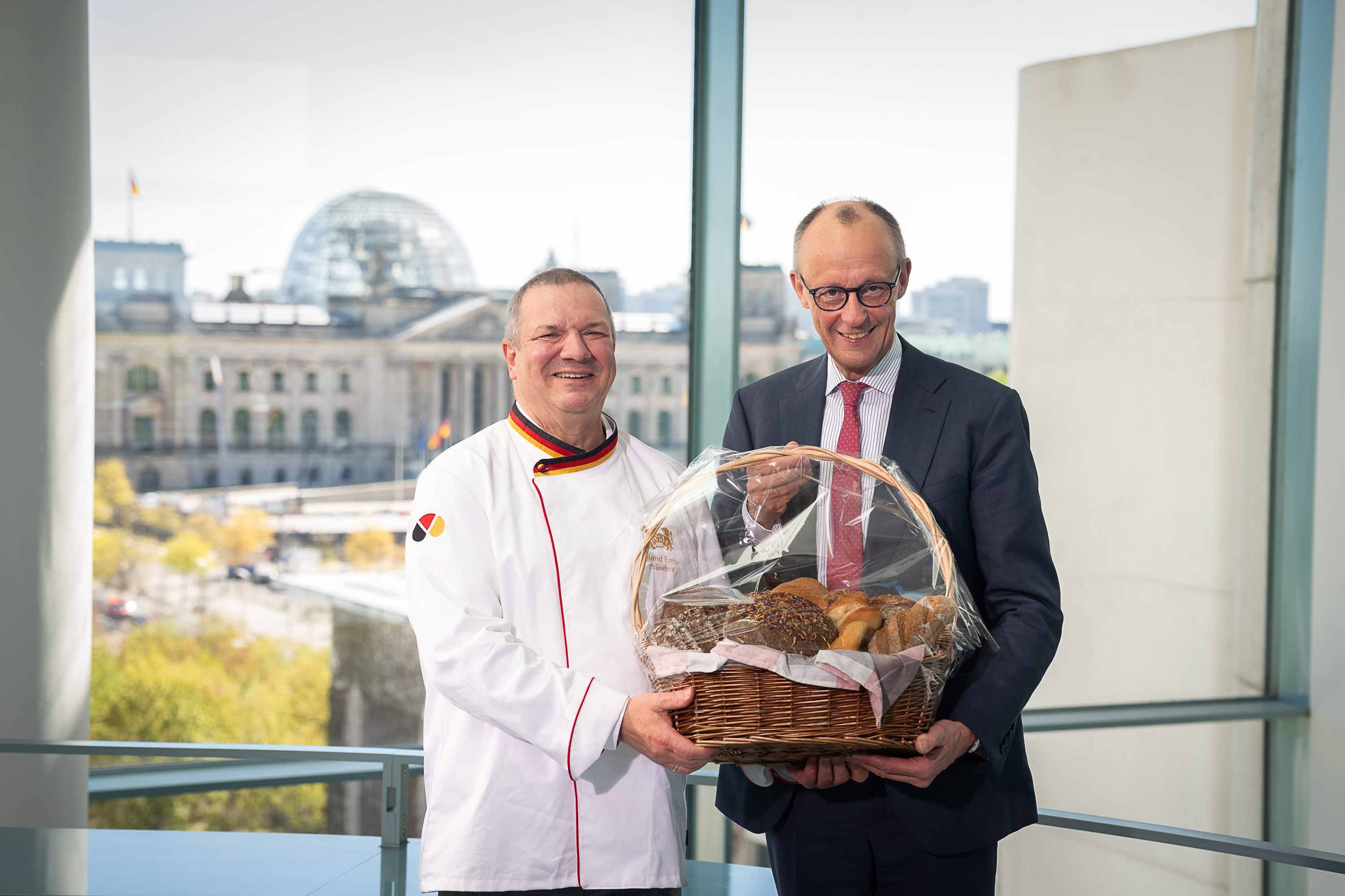 Roland Ermer &uuml;berreicht Friedrich Merz den Brotkorb im Bundeskanzleramt.. Foto: © Bundesregierung_Steffen Kugler