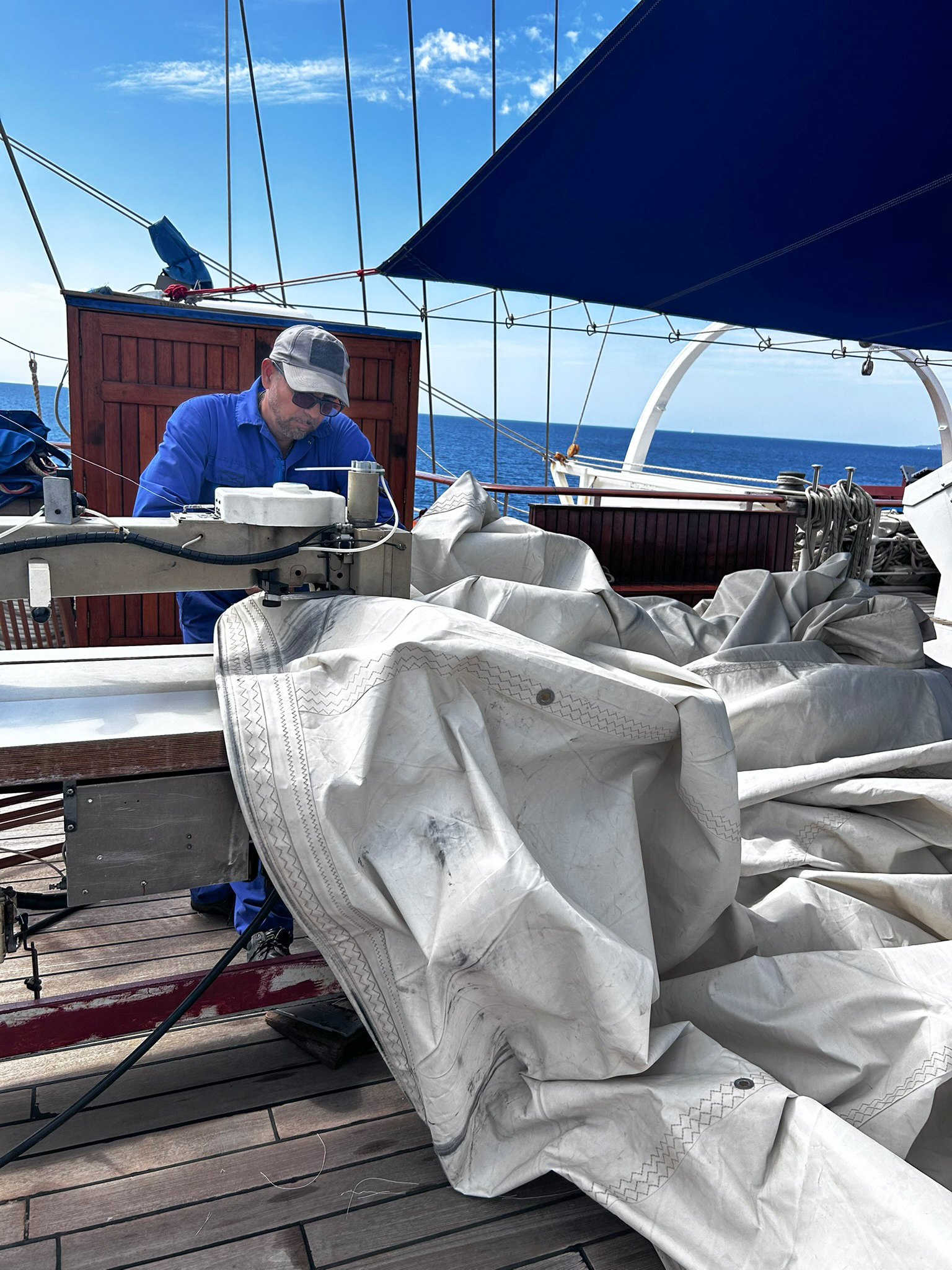 Matrose Oscar an der N&auml;hmaschine an Deck des Segelschiffes. Bei 42 Segeln stehen fast t&auml;glich Reparaturarbeiten an. Foto: © DHB