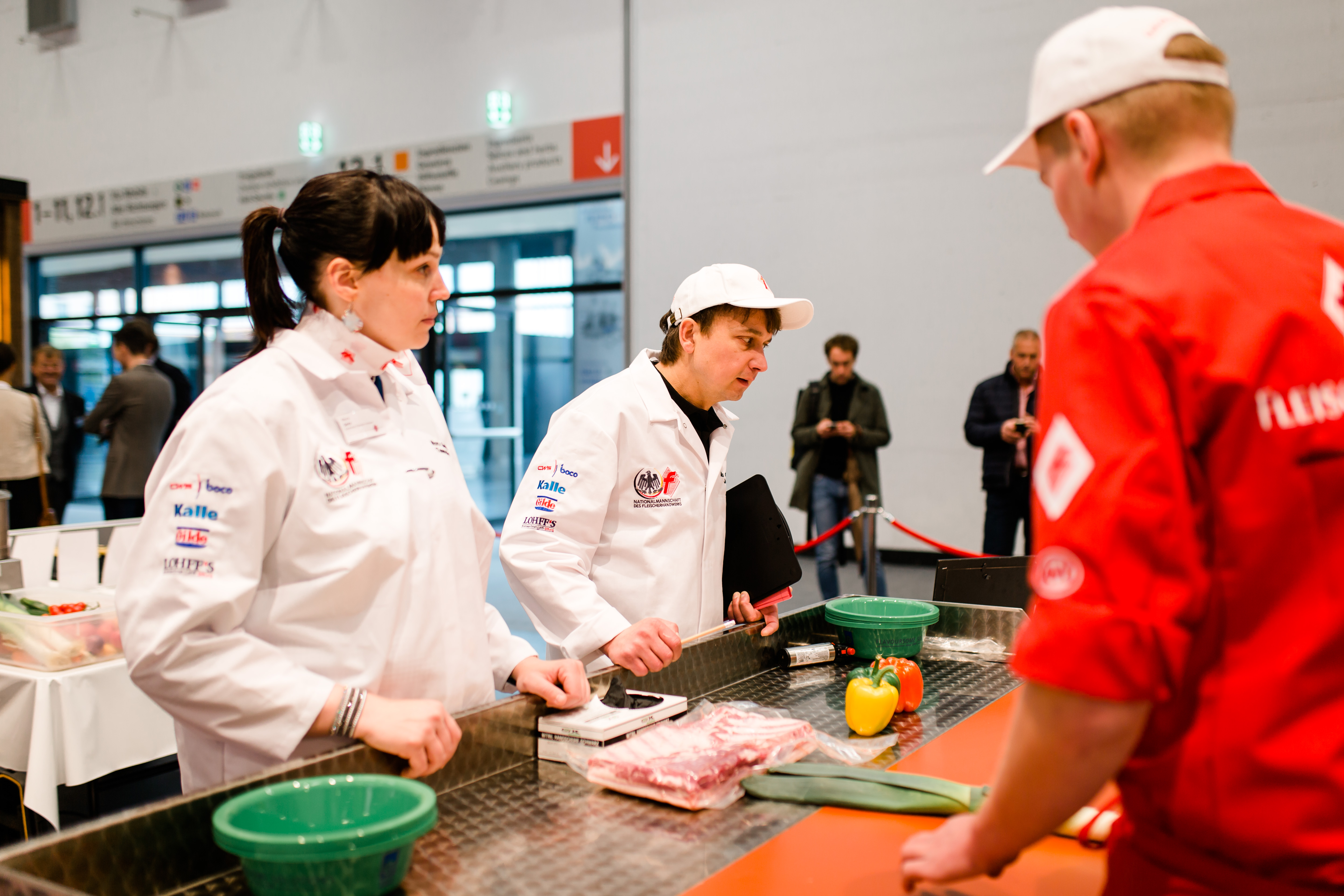 Chef-Trainer Max Gruber (Mitte) und Team-Chefin Nora Seitz prüfen beim internationalen Leistungswettbewerb der Fleischerjugend in Frankfurt kritisch die Arbeit eines deutschen Teilnehmers. Foto: © Deutscher Fleischer-Verband