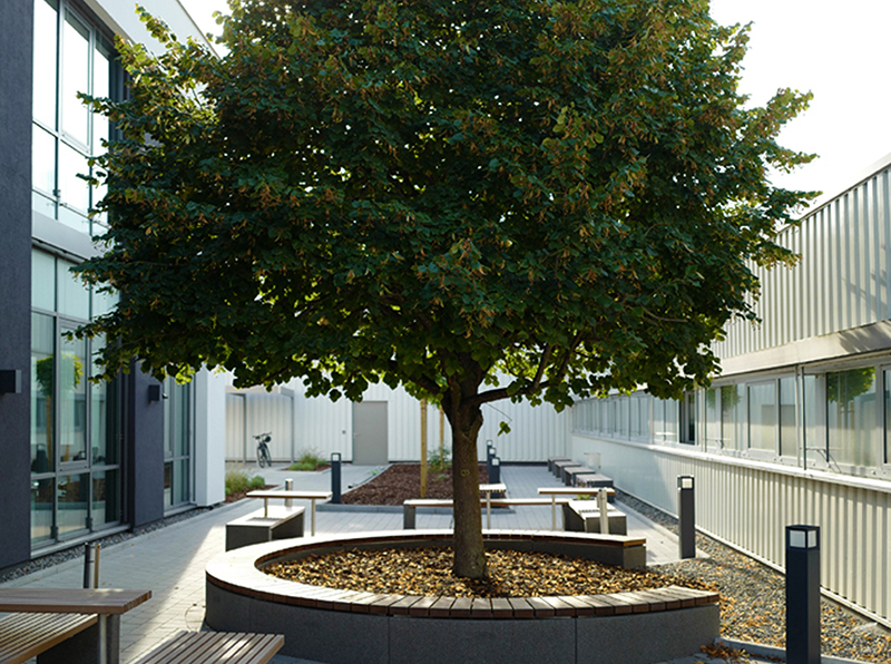 Durch den begrünten Innenhof mit zahlreichen Sitzgelegenheiten ist ein attraktiver Übergang vom Produkt- und Schulungszentrum zum Bestandsgebäude entstanden. Foto: © Berner Torantriebe