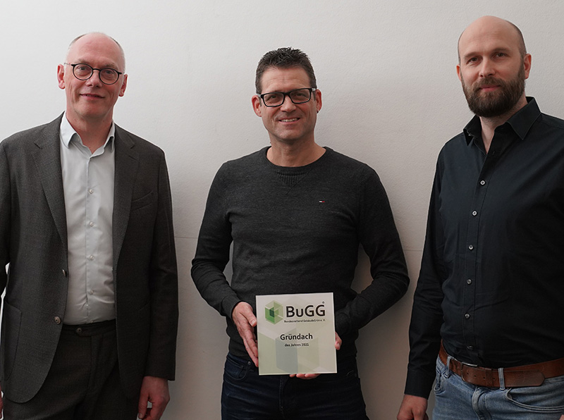 BuGG-Präsident Dr. Gunter Mann (Mitte) überreicht den Geschäftsführern von Landschaftsarchitektur+ Felix Holzapfel-Herziger (links) und Julian Benesch die Siegerplakette zum BuGG-Gründachdes Jahres 2021. Foto: © Landschaftsarchitektur+ / BuGG
