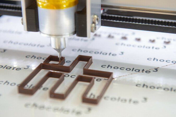 Schokolade aus dem 3D-Drucker: Buchstaben, ganze Sätze oder das IHM-Logo stellt Konditormeister Benedikt Daschner aus feinster Schweizer Schokolade her – mit Hilfe eines 3D-Druckers. Foto: © GHM Foto: © GHM